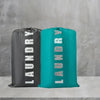 Two reusable laundry storage bags, one black and one teal, standing on a light gray shelf.