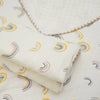 A rolled white cotton gauze baby swaddle blanket with a bear print pattern lying on a white fabric background.