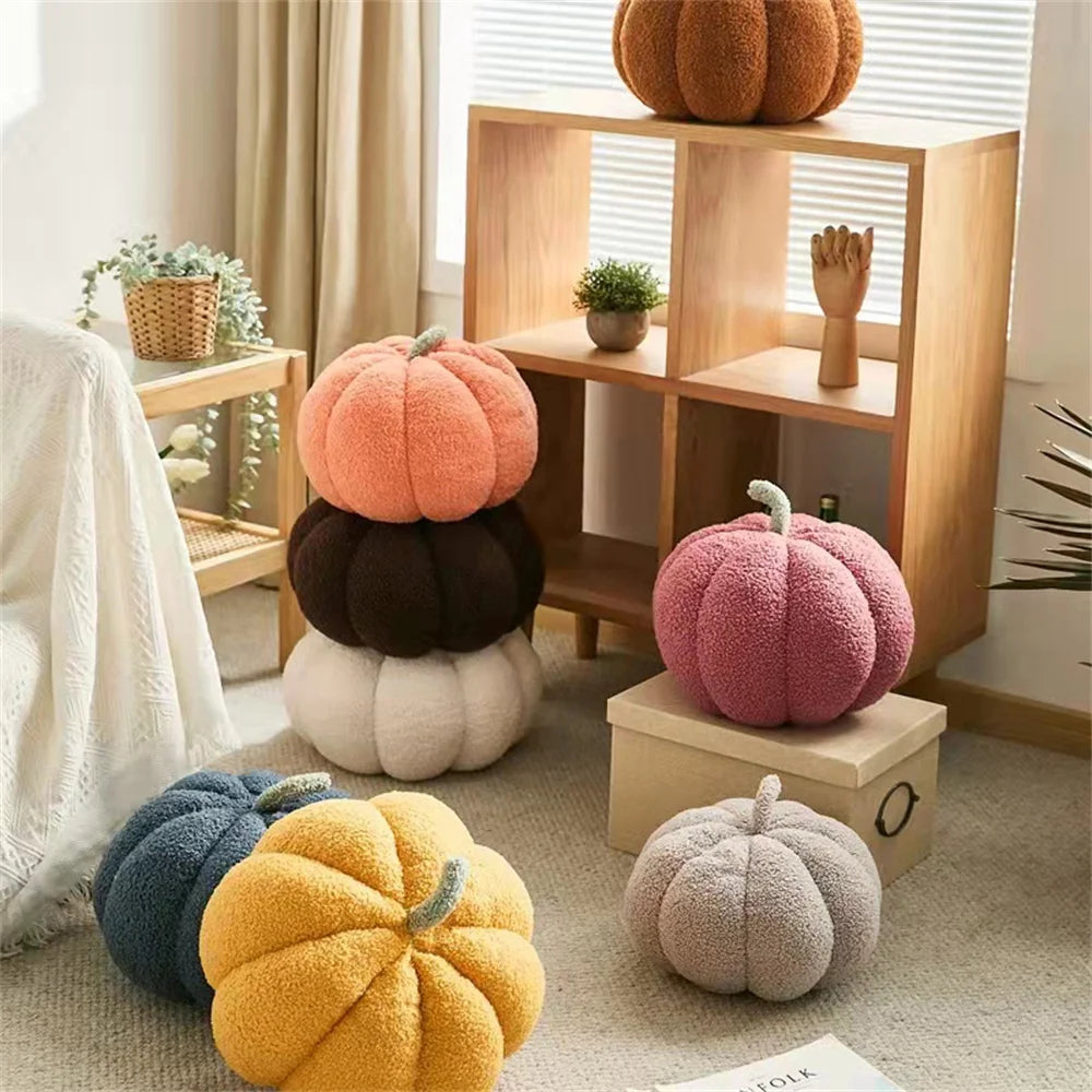 A collection of soft, round decorative pumpkins in various colors like orange, pink, and yellow displayed on wooden shelves.