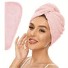 A woman is wearing a pink microfiber hair drying towel wrap on her head.