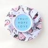 A reusable multi-use ice and heat therapy pack made of white fabric with pink fruit designs.