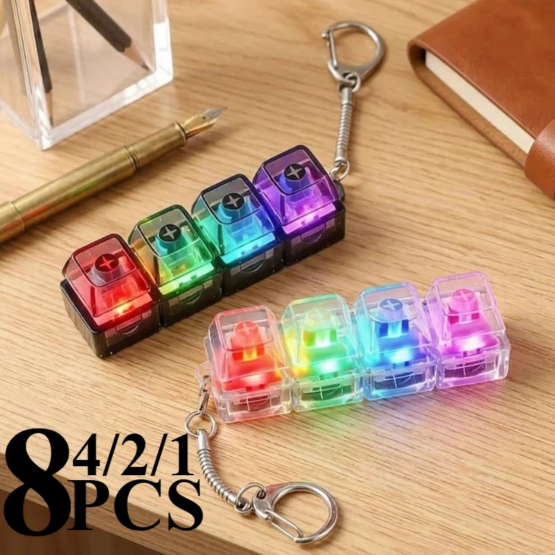 Eight pieces of LED clickable fidget keychains shaped like keyboards are displayed on a wooden surface.