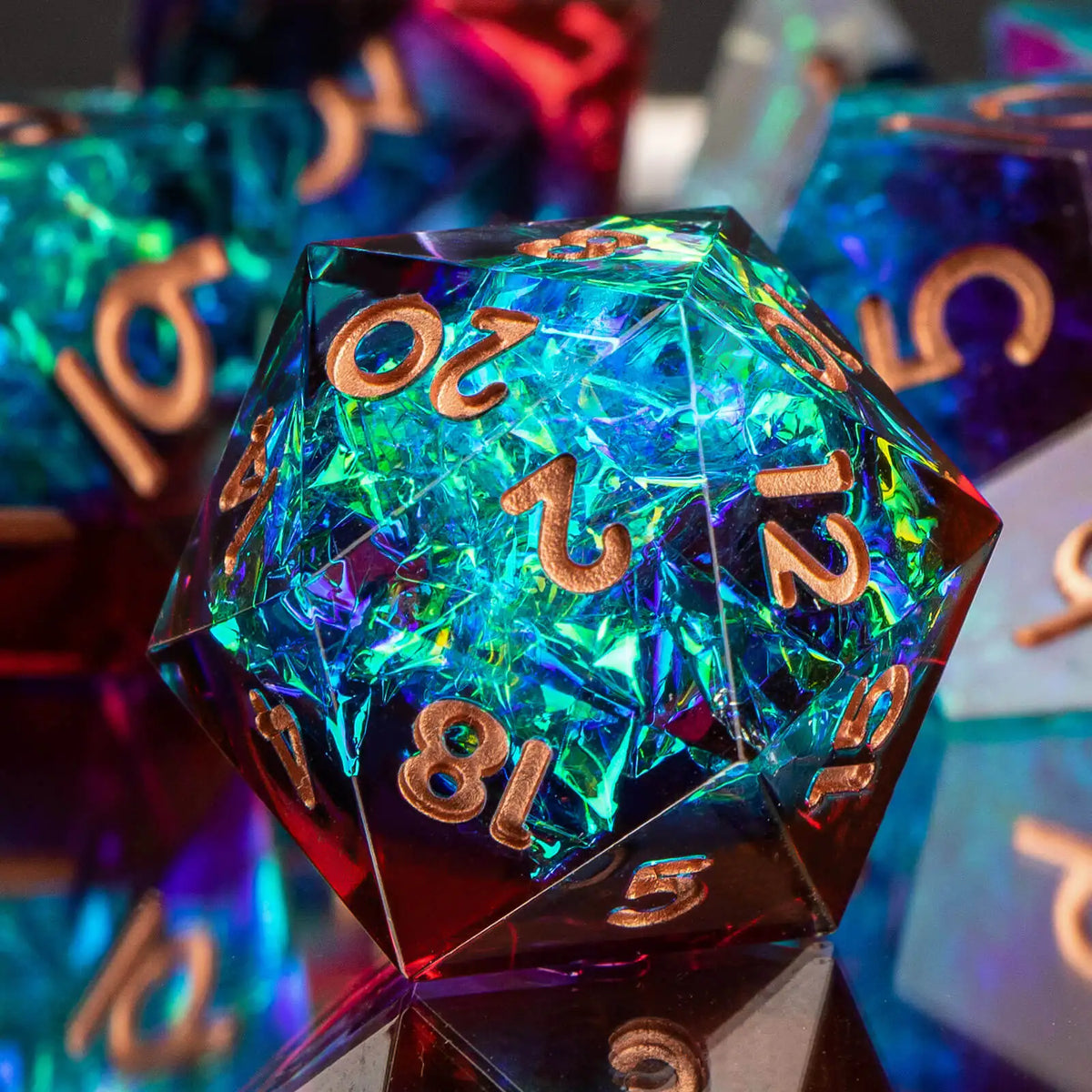 A close-up of a translucent blue and green polyhedral die resting on a reflective surface.