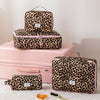 A leopard print toiletry bag in brown and black spots resting on a pink storage box.