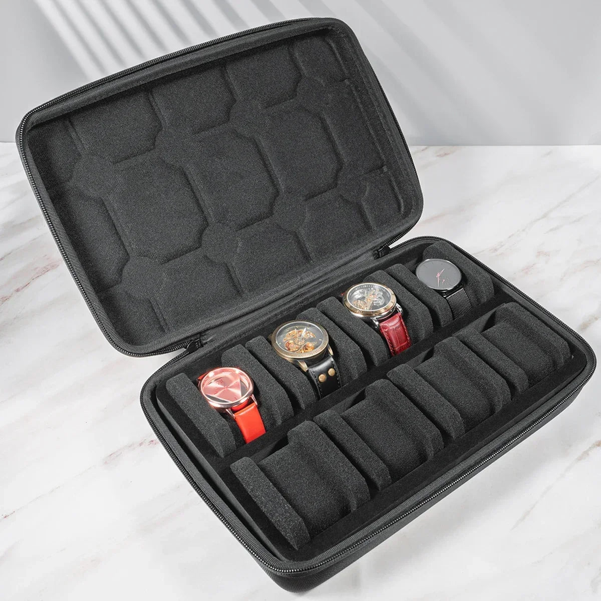 A black portable leather watch travel case with a soft lining, open to display several watches.