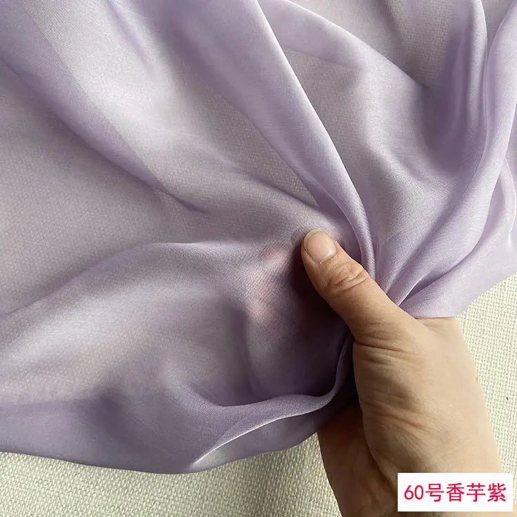 Close-up of light purple silk chiffon fabric being held and draped