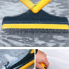 A dark blue and yellow 2-in-1 floor scrub brush with a squeegee is shown cleaning a wet, mottled surface.