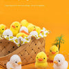 A pile of yellow and white chick toys is displayed on a wooden surface with small white seeds.