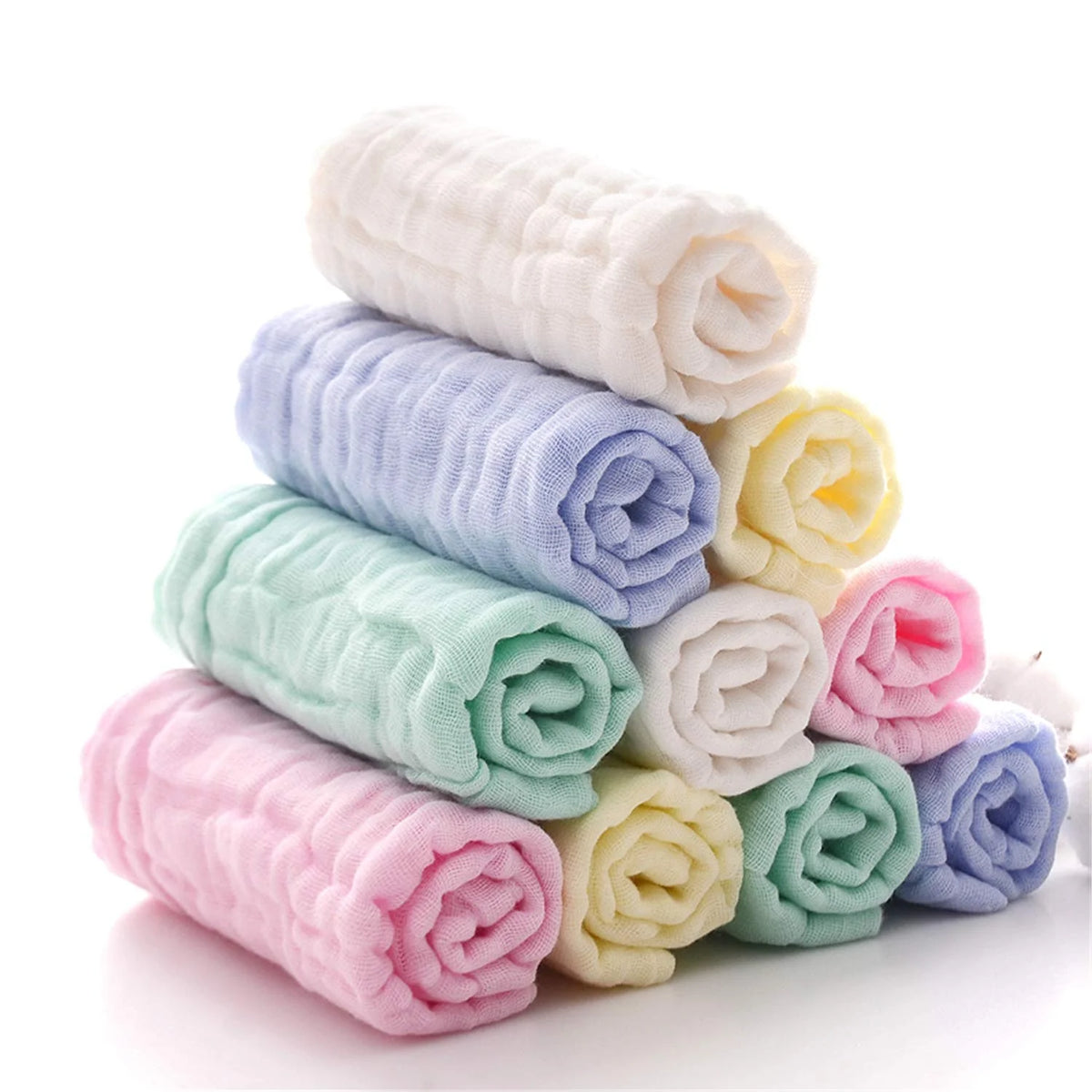 A stack of pink, blue, and green soft natural cotton muslin baby washcloths rolled into cylinders.