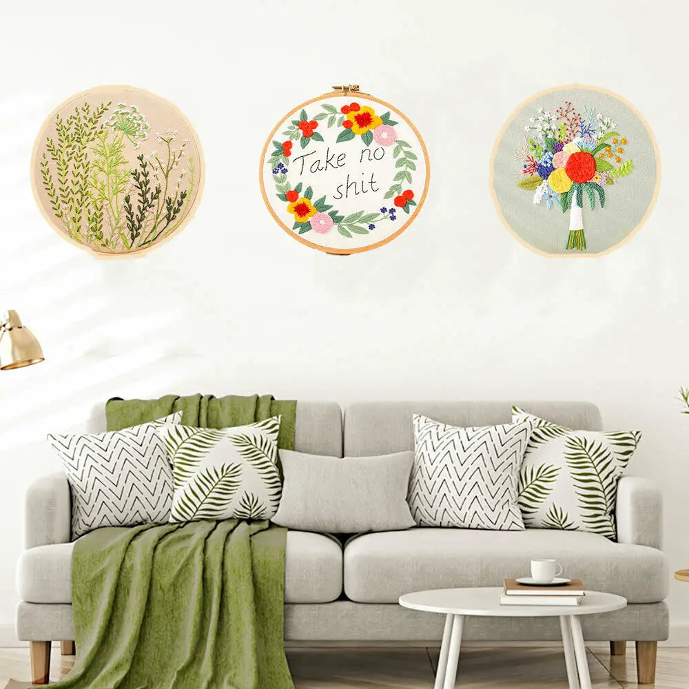 A set of floral cross stitch embroidery kits featuring various colored flowers and greenery on circular wooden boards.