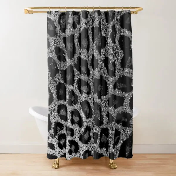 A black and white leopard print shower curtain hanging from a gold rod.