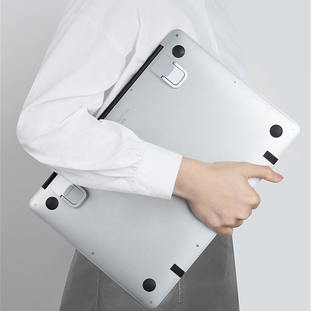 A person holds an aluminum portable laptop stand, showing its design and adjustable legs.