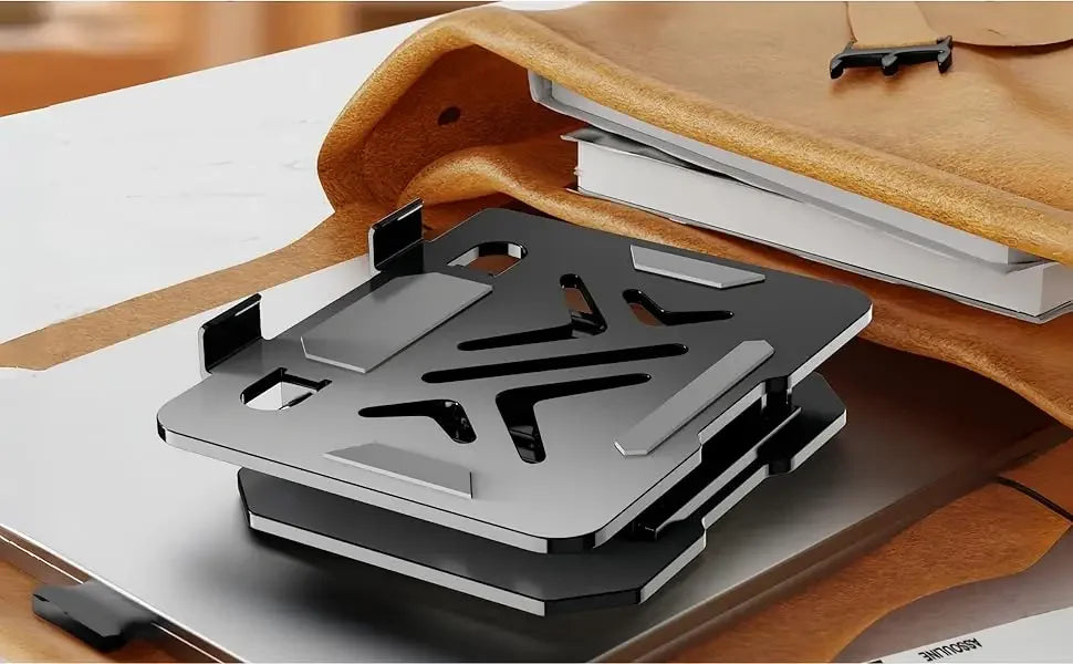 A silver carbon steel tablet stand is shown resting on a light-colored desk next to a brown leather folder.