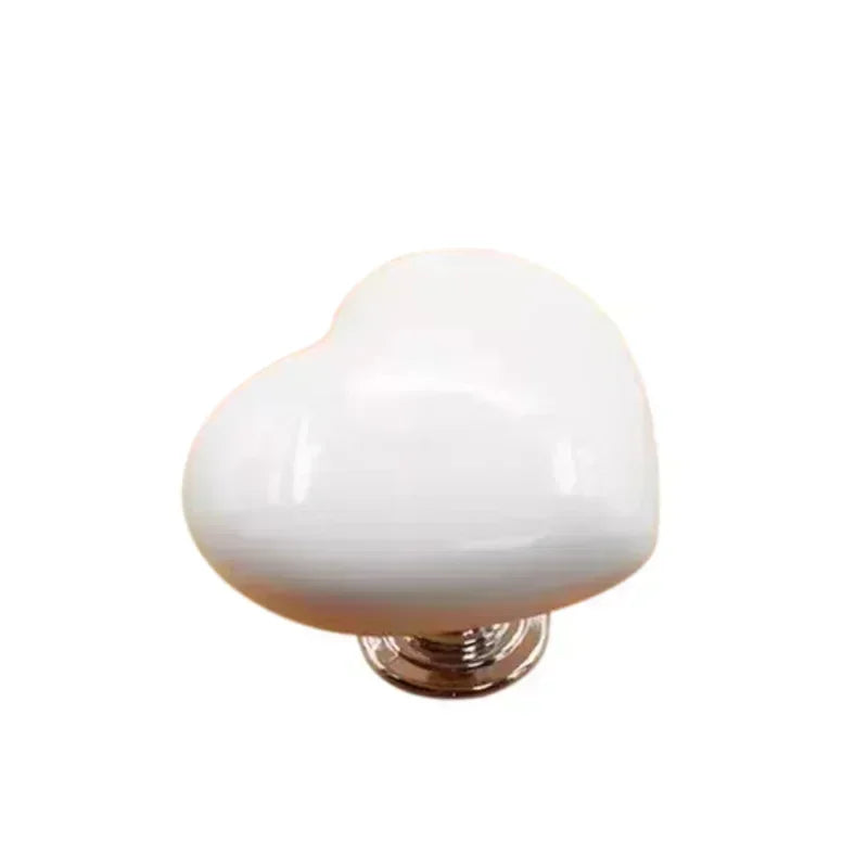 White heart-shaped toilet flush button with a nail protector.