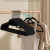 Black premium velvet hangers with 360° swivel hooks hanging on a wooden rod.