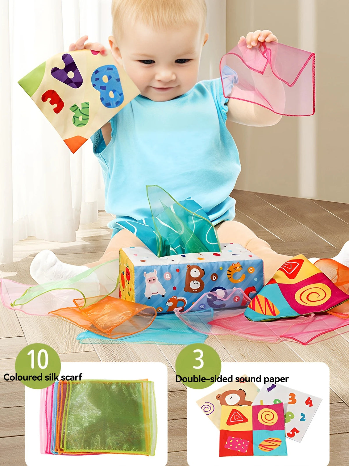 A baby holds a pink silk scarf and a colorful cloth book toy featuring cartoon animals.