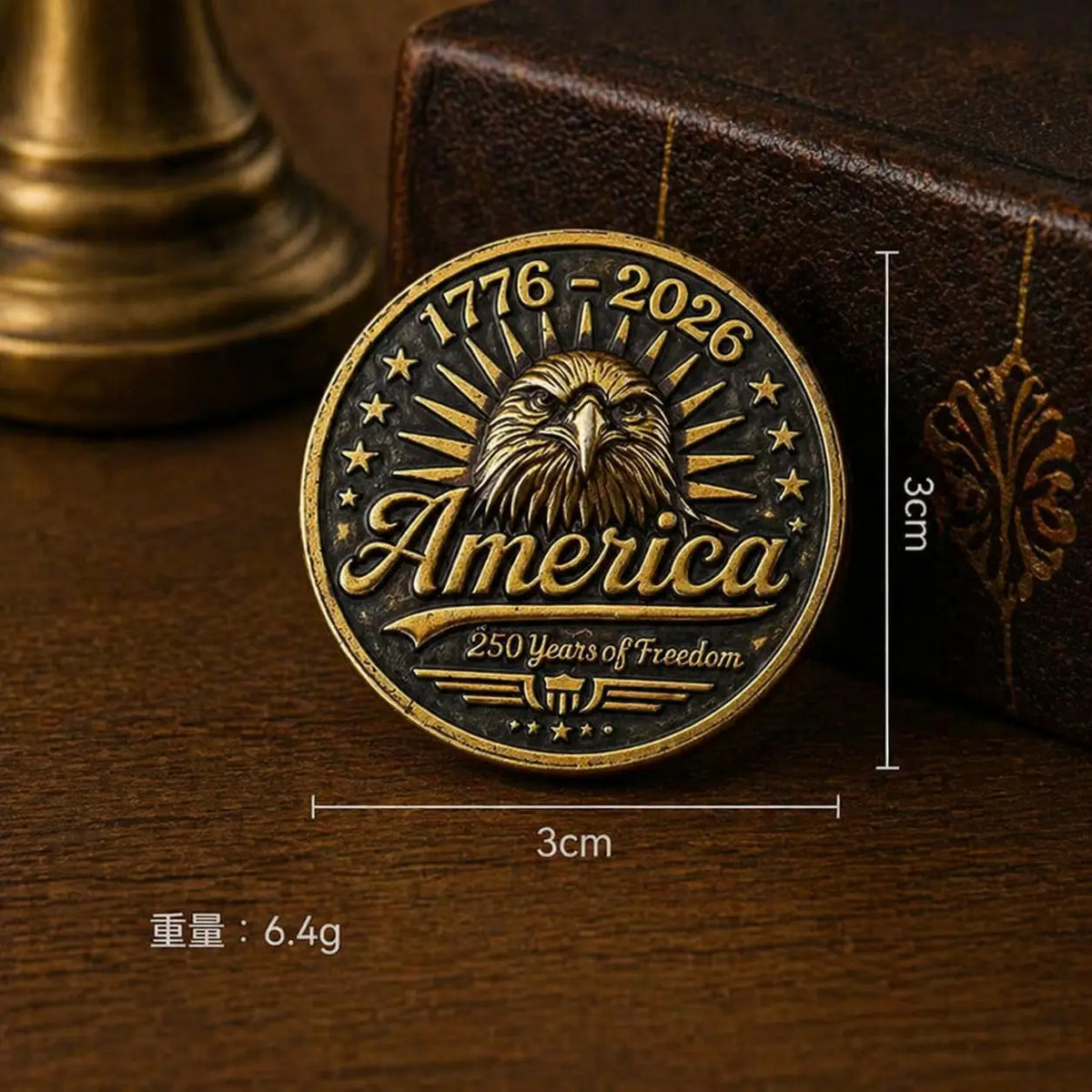 A round brass enamel pin featuring an American eagle design and the text 1776-2026 surrounded by stars.