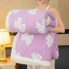 A purple plush jacquard throw blanket with white butterfly patterns is draped over a person's arm.
