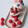 Dessert pink et blanc avec fraises et crème sur un plateau.