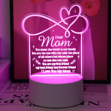 A glowing pink heart-shaped sign featuring a handwritten message to Mom on a white base.