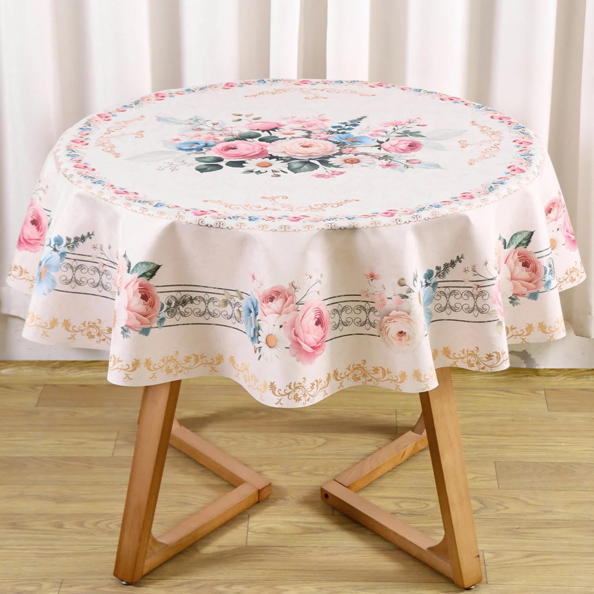 Vintage floral tablecloth with pink and blue roses on a round dining table.