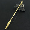 A gold-colored metal sword keychain with an ornate tip is displayed against a dark background.