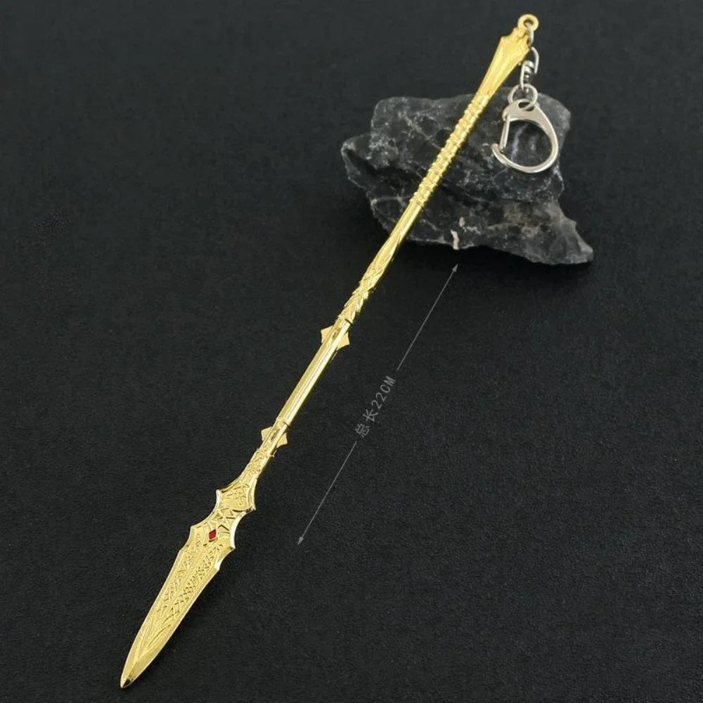 A gold-colored metal sword keychain with an ornate tip is displayed against a dark background.