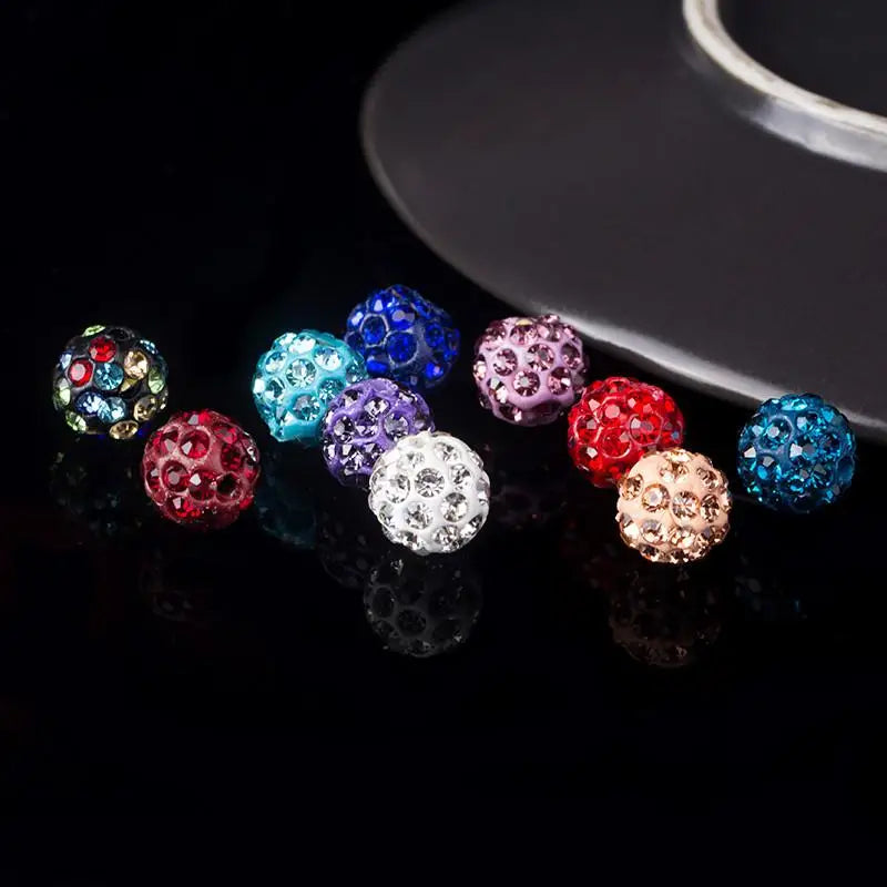 A collection of colorful crystal clay round beads in various shades including blue, purple, red, and clear, displayed on a da