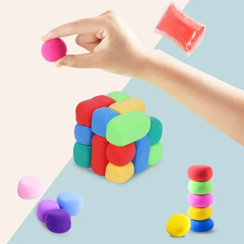 Eine Hand hält einen rosa Schlammball, mit verschiedenfarbigen Schlammbällen auf einer hellblauen Oberfläche verteilt.