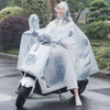 A person wearing a transparent waterproof motorcycle rain poncho with a hood is sitting on a motorcycle on a wet road.