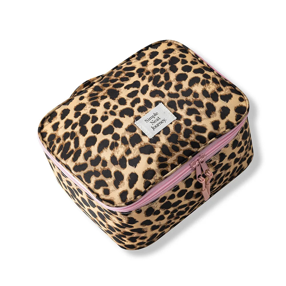 A leopard print toiletry bag with a pink zipper and a small tag is shown on a white background.