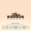 A black silhouette design featuring the words Home The Lucas Family above a row of iron wall hooks.
