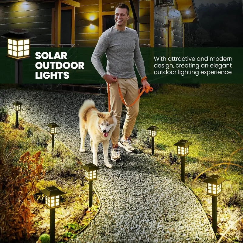 Un homme marche avec un chien sur un chemin de gravier éclairé par des lumières solaires extérieures.