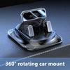 A silver 360 degree rotating car mount with a clear phone holder and anti-slip silicone base resting on a dark surface.