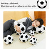 A woman rests her head on a collection of soft, black and white football plush pillows.