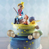 Mehrstöckige Torte mit Figur einer blonden Figur und goldenen Kugendekorationen.