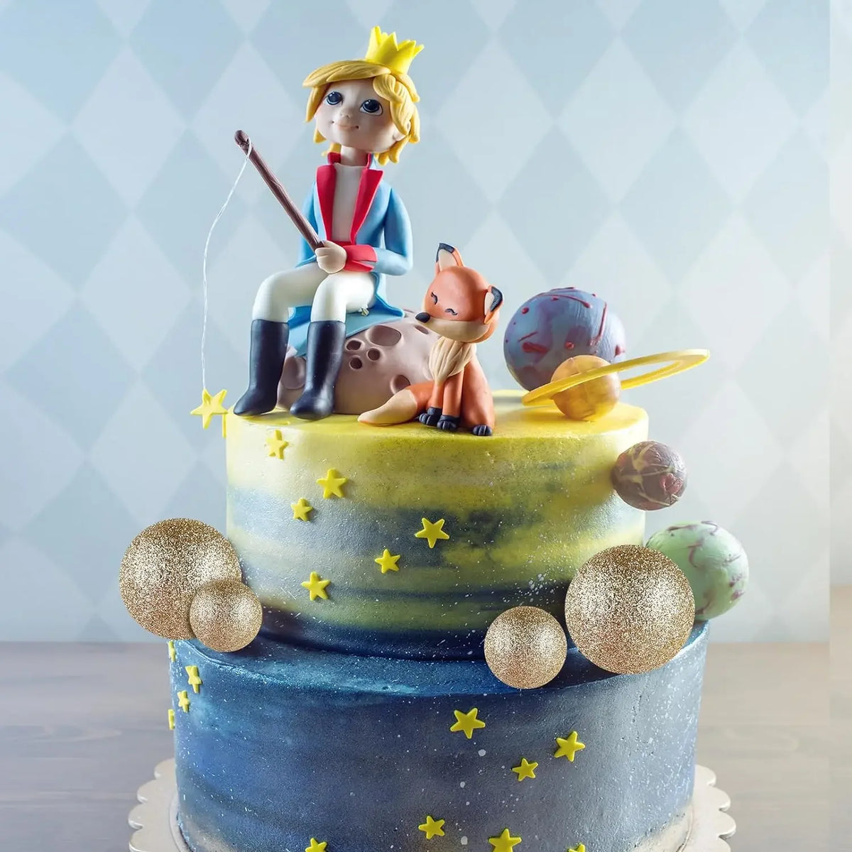 Mehrstöckige Torte mit Figur einer blonden Figur und goldenen Kugendekorationen.