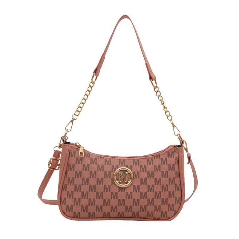 A vintage-inspired pink PU leather crossbody bag with a gold chain strap and a metal M accent.
