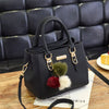 Black vintage PU leather tassel shoulder bag with gold hardware and fur pom-poms resting on a wooden surface.
