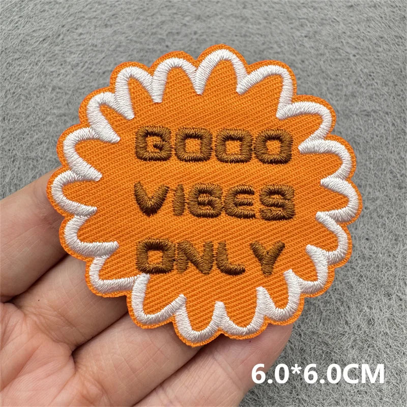 Orange embroidered iron-on patch with text GOOD VIBES ONLY on a gray background