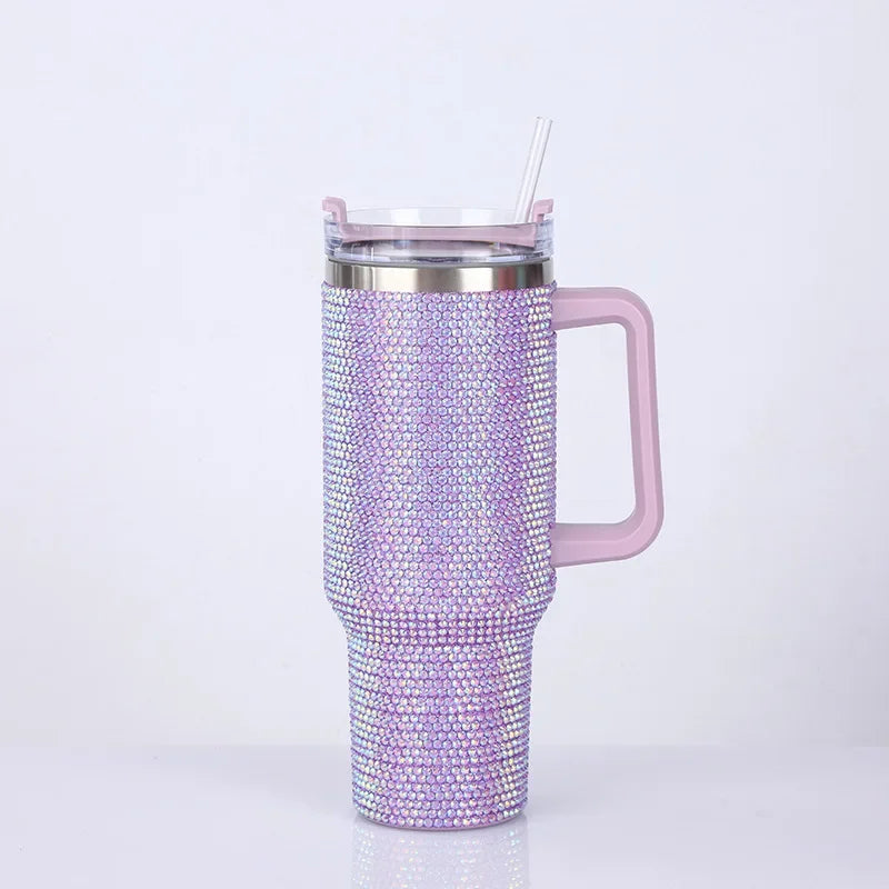 A purple rhinestone bling tumbler with a silver lid, straw, and handle.