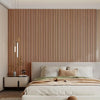 A bedroom featuring a wooden slat wall panel behind a bed with white linens and neutral tones.