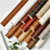 Rolls of self-adhesive wood grain wallpaper in various shades of brown and beige.