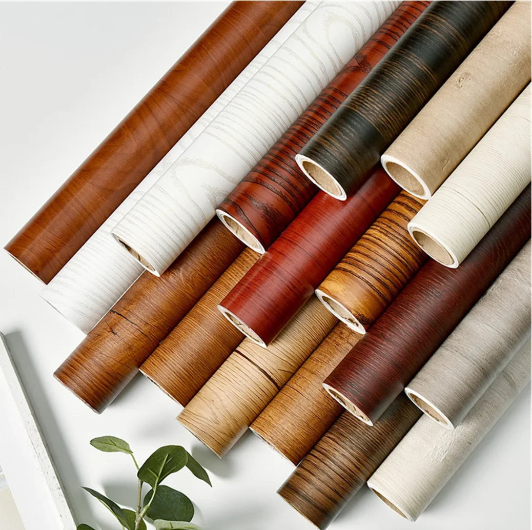 Rolls of self-adhesive wood grain wallpaper in various shades of brown and beige.