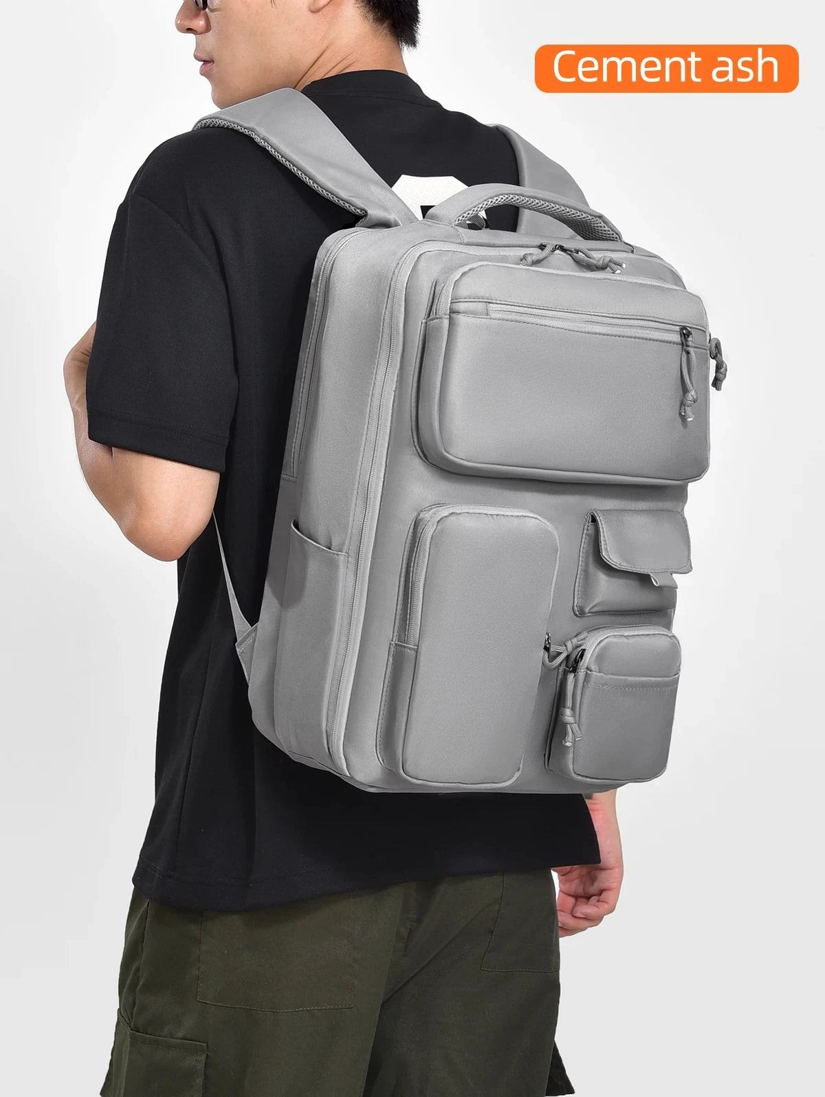 A person is carrying a gray cement ash travel backpack with a laptop compartment.