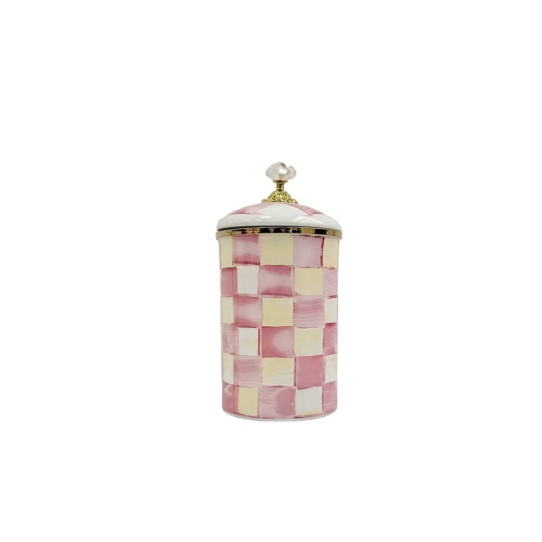 A ceramic storage jar with a pink and cream checkerboard pattern and a gold lid.