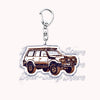 A silver metal key ring featuring a detailed illustration of an off-road truck.