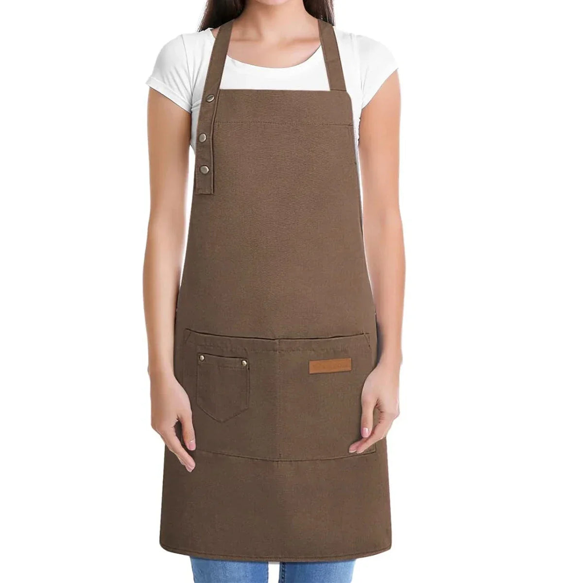 A brown canvas apron with multiple pockets is shown being worn over a white shirt.
