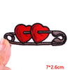 A set of embroidered iron-on patches featuring two red heart shapes on a black fabric background.