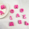 Perles de lettres acryliques roses formant le mot MOWLAZ et des lettres individuelles comme L, A, Z, B.